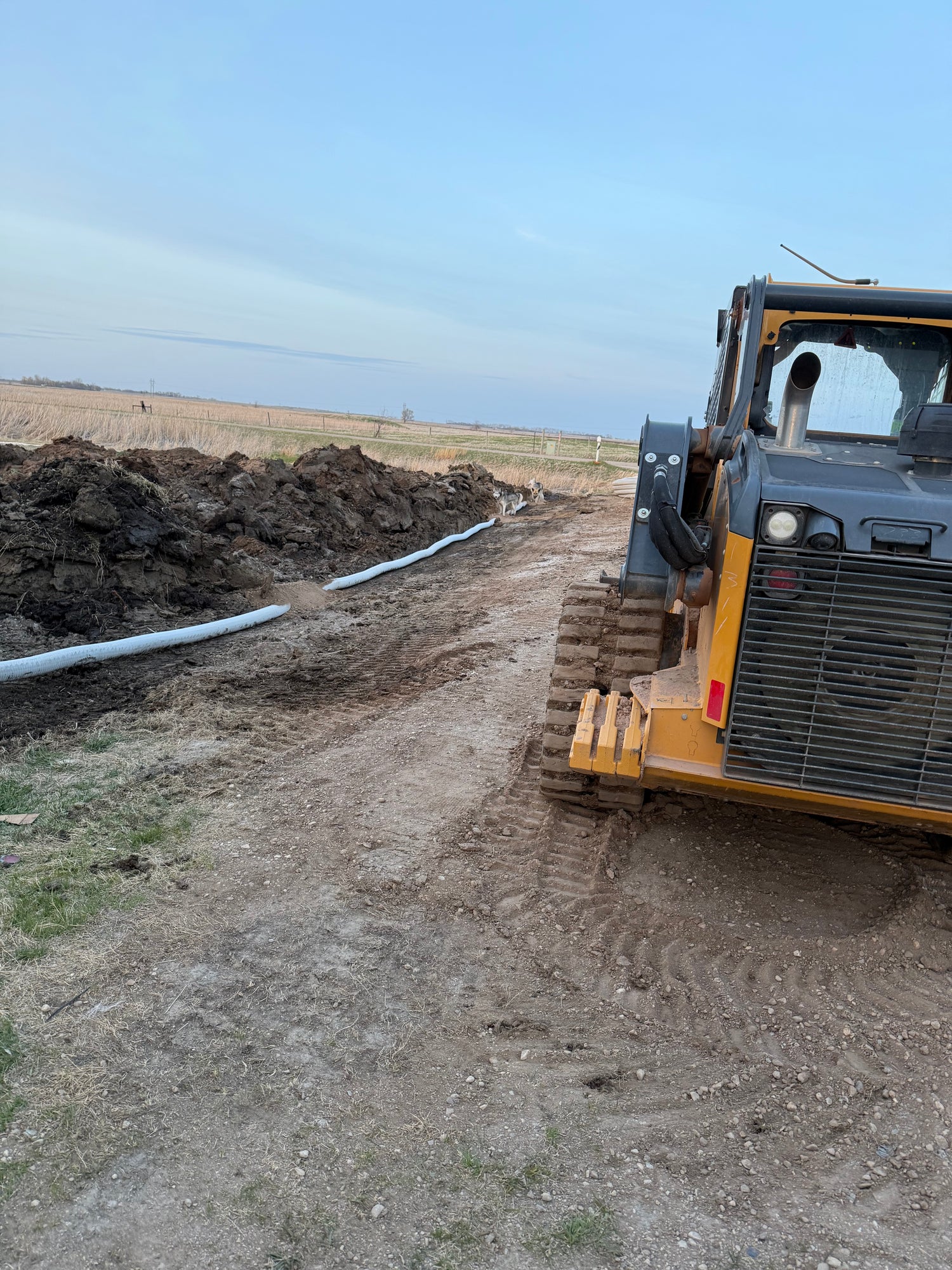 Yellow bulldozer on a dirt field with a clear sky